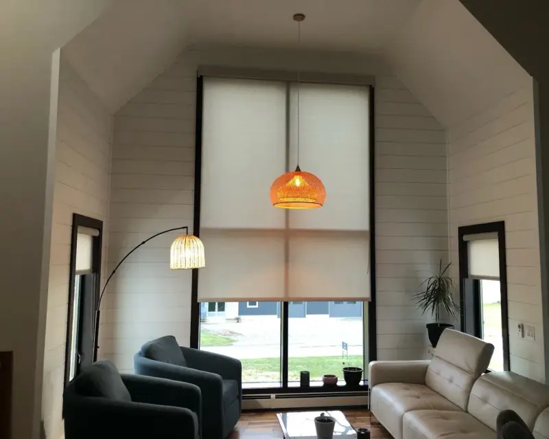 Light-filtering roller shades on a two-story great room window above a sofa