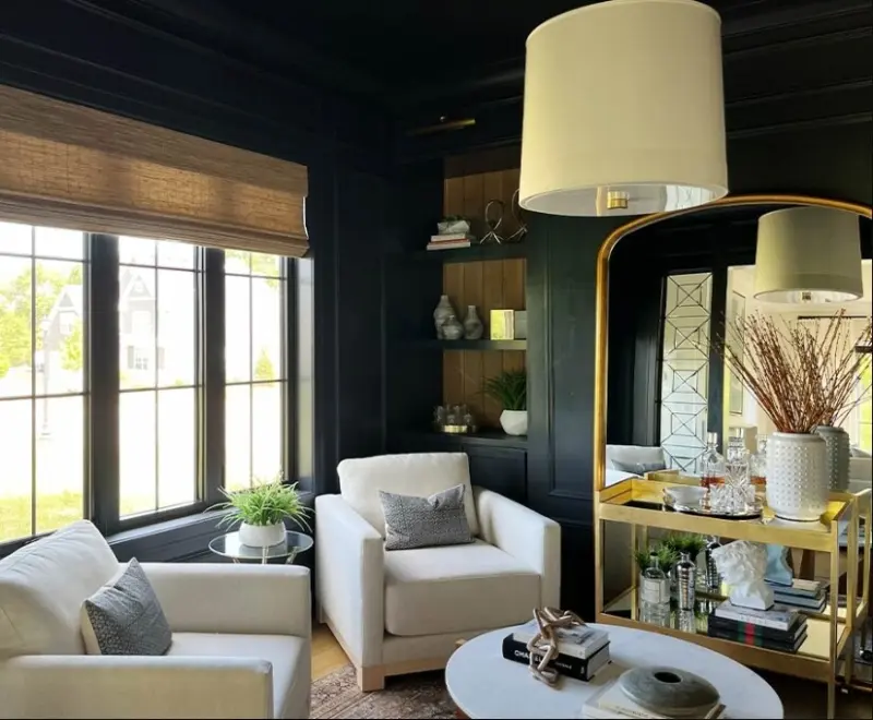 Woven wood shade on a window in a dark-panelled sitting room with white armchairs